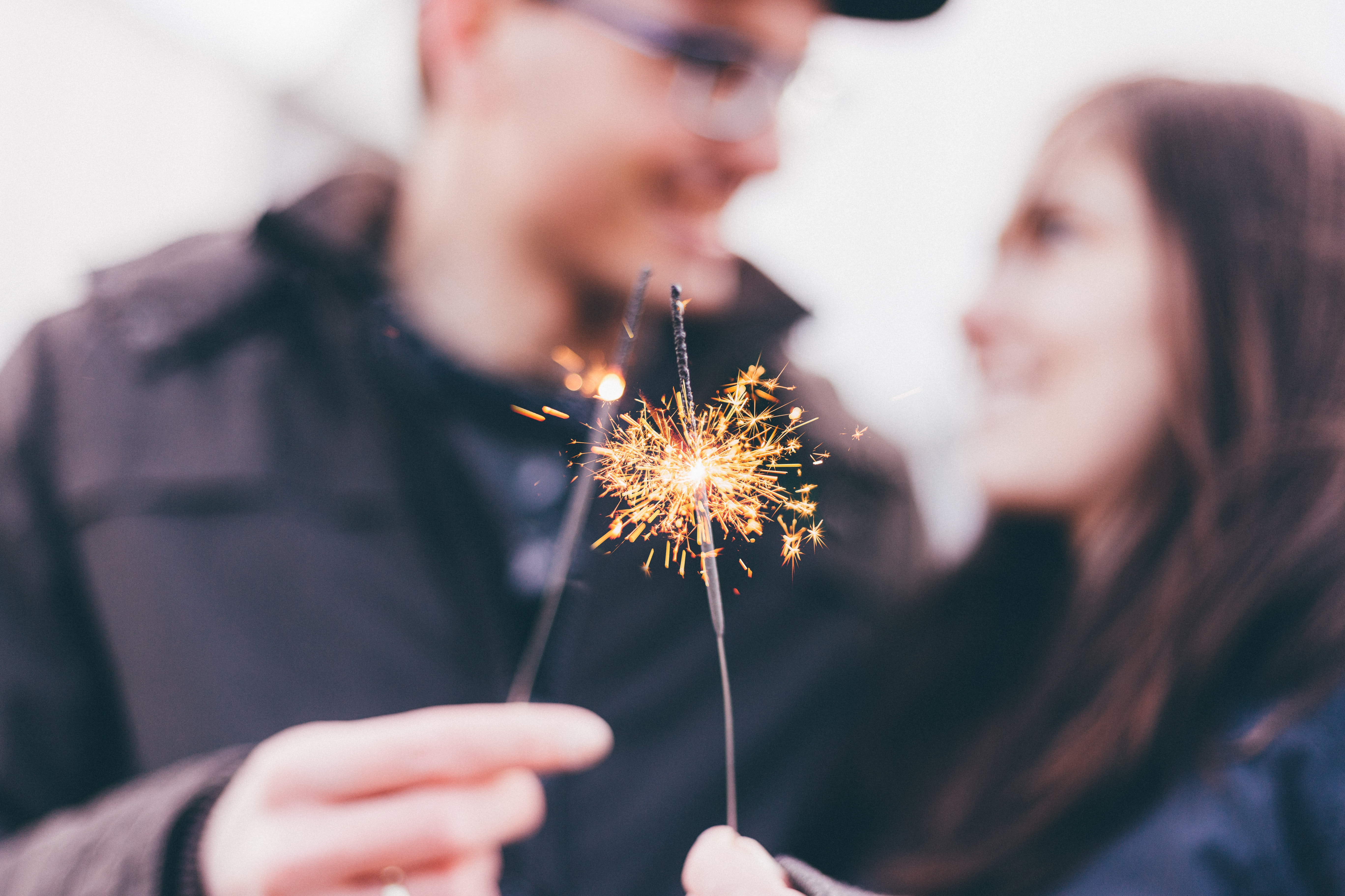 A man and woman out of focus holding sparklers.
